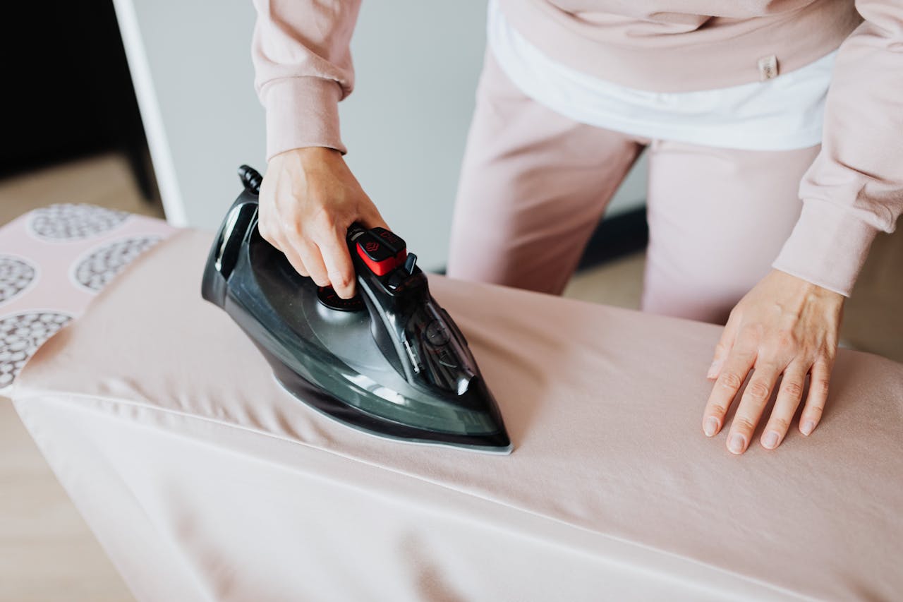 The Art of Drawing Readers In: Your attractive post title goes here Adult woman ironing clothing on board using a black iron in an indoor setting.